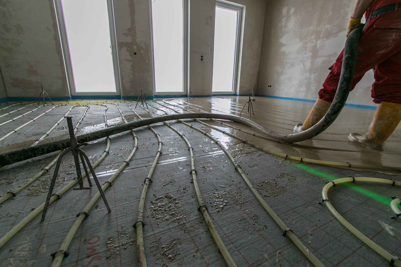 Coulage d’une chape fluide sur plancher chauffant dans une pièce en travaux